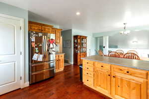 Kitchen with freestanding refrigerator, a notable chandelier, recessed lighting, baseboards, and dark wood-style flooring