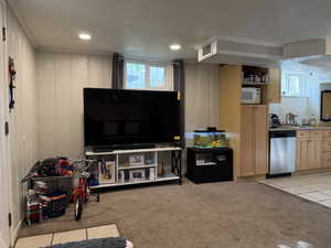 Living area featuring light colored carpet, a wealth of natural light, visible vents, and ornamental molding