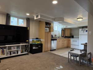 Kitchen with white appliances, light colored carpet, a textured ceiling, open shelves, and light brown cabinets