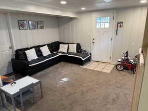 Carpeted living area featuring a decorative wall and tile patterned flooring