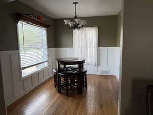 Dining area featuring a decorative wall, wainscoting, and wood finished floors