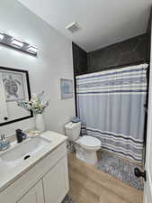 Bathroom with visible vents, vanity, wood finished floors, toilet, and a textured ceiling