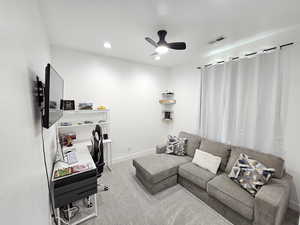 Carpeted living room featuring a ceiling fan, baseboards, visible vents, and recessed lighting