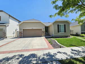 Ranch-style home featuring an attached garage, driveway, a front yard, and stucco siding