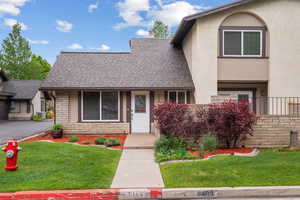 View of front of house featuring central air condition unit, a shingled roof, and a front yard