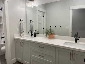 Full bathroom with double vanity, a sink, tile patterned flooring, and toilet