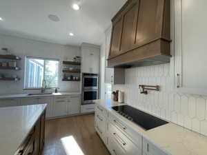 Kitchen with a sink, open shelves, double oven, and black electric cooktop