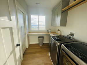 Washroom featuring visible vents, cabinet space, a sink, light wood finished floors, and washer and clothes dryer