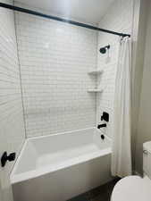 Bathroom with shower / tub combo, tile patterned floors, and toilet