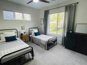 Carpeted bedroom with visible vents, ceiling fan, and multiple windows