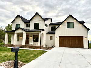 Modern inspired farmhouse with an attached garage, board and batten siding, a porch, and a front yard