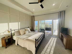 Bedroom with light colored carpet, visible vents, a raised ceiling, access to outside, and a decorative wall