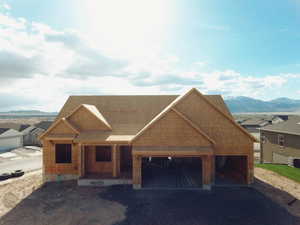 View of front of property featuring a mountain view, covered porch, an attached garage, gravel driveway, and central AC unit
