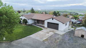 Ranch-style house with a mountain view, a front lawn, a garage, and covered porch