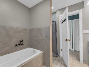 Main Full bathroom with a garden tub and wood finished floors