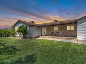 Front of property at dusk with a lawn and a chimney