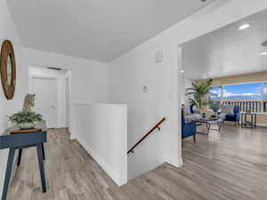 Hallway with light wood finished floors,  and and stairs leading to basement