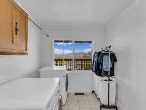 Laundry room with light tile patterned flooring, washing machine and clothes dryer, and cabinet space