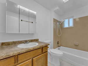 Bathroom featuring tile patterned flooring, toilet, shower / tub combination, and vanity