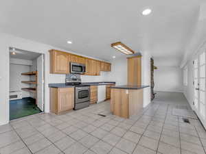 Kitchen with dark countertops, appliances with stainless steel finishes, and pantry