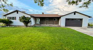 Single story home with concrete driveway, a front lawn, and an attached garage