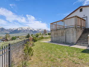 View of yard featuring stairs, a deck with mountain view, and a fenced backyard
