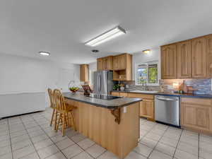 Kitchen with a sink, stainless steel appliances, a kitchen bar, and decorative backsplash
