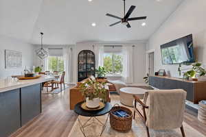 Living room featuring vaulted ceiling, ceiling fan, light wood-type flooring, and recessed lighting