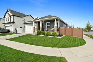 View of front of home featuring a porch, an attached garage, a front yard, and driveway