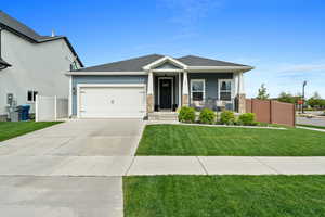 View of front of property with fence, covered porch, an attached garage, concrete driveway, and a front lawn