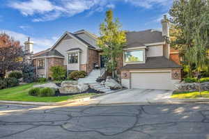 View of front of house featuring driveway, an attached garage, and a chimney