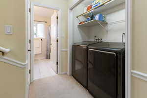 Laundry area with independent washer and dryer, light carpet, light tile patterned flooring, and laundry area