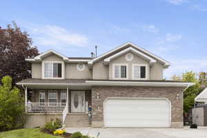 Traditional-style house featuring covered porch, brick siding, driveway, a garage, and stucco siding