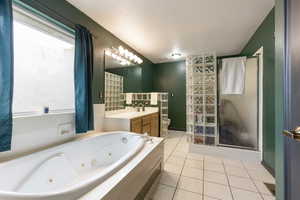 Bathroom with toilet, tile patterned floors, a whirlpool tub, and a stall shower