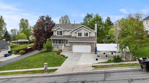Traditional home with an attached garage, concrete driveway, brick siding, stucco siding, and roof with shingles