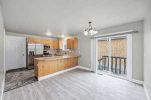 Kitchen with a sink, an inviting chandelier, stainless steel appliances, and a healthy amount of sunlight