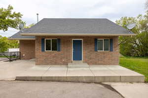 View of front of home featuring fence, a shingled roof, and brick siding