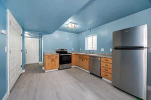 Kitchen with a sink, light countertops, baseboards, and appliances with stainless steel finishes