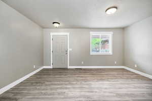 Spare room featuring a textured ceiling, baseboards, visible vents, and wood finished floors