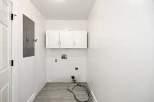 Clothes washing area featuring electric dryer hookup, cabinet space, washer hookup, electric panel, and baseboards