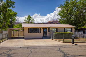 Ranch-style house featuring metal roof, fence, a carport, and concrete driveway