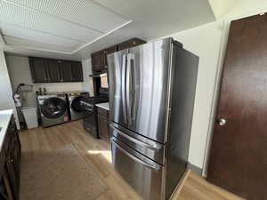 Kitchen featuring stainless steel appliances, light wood-type flooring, dark wood finish cabinetry, and washer and dryer