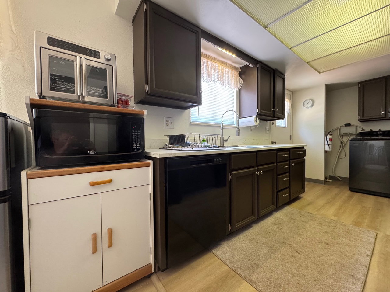 Kitchen with black appliances, washer / dryer, light wood-style flooring, and new ight countertops