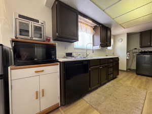 Kitchen with black appliances, washer / dryer, light wood-style flooring, and new ight countertops