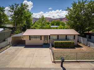 Ranch-style house featuring metal roof, concrete driveway, a mountain view, and an attached carport