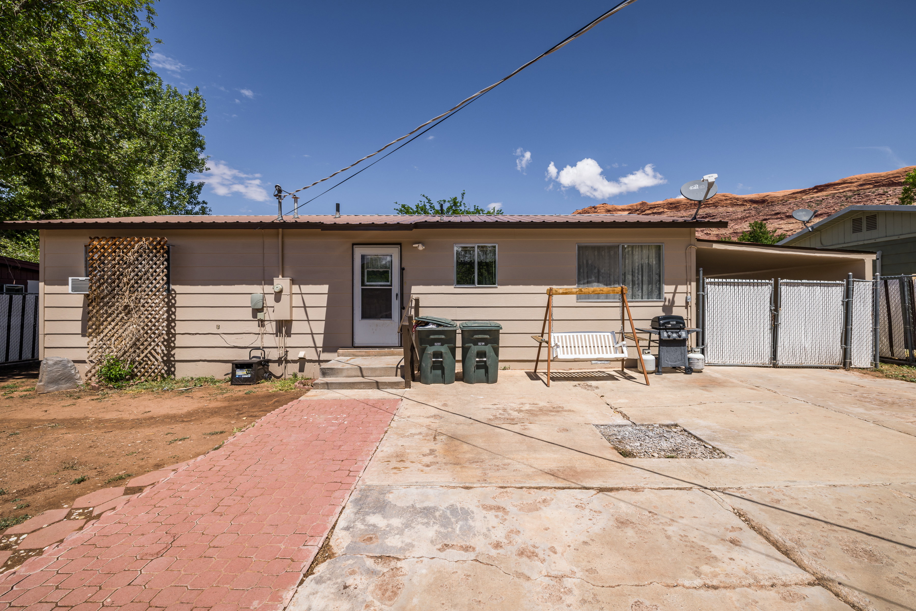 View of rear facade with fence, a carport, and a gate