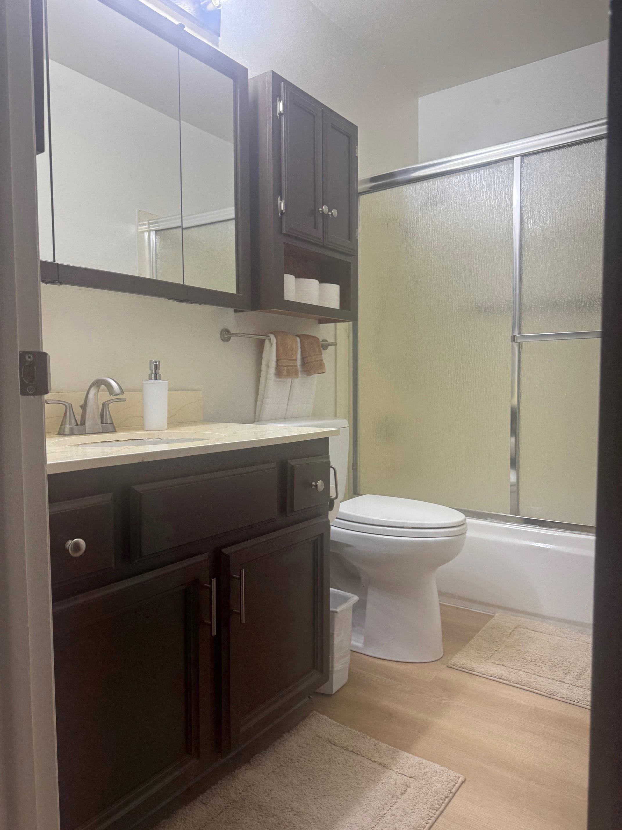 Bathroom featuring vanity, LVP finished floors, and shower / bath combination with glass door