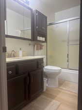 Bathroom featuring vanity, LVP finished floors, and shower / bath combination with glass door