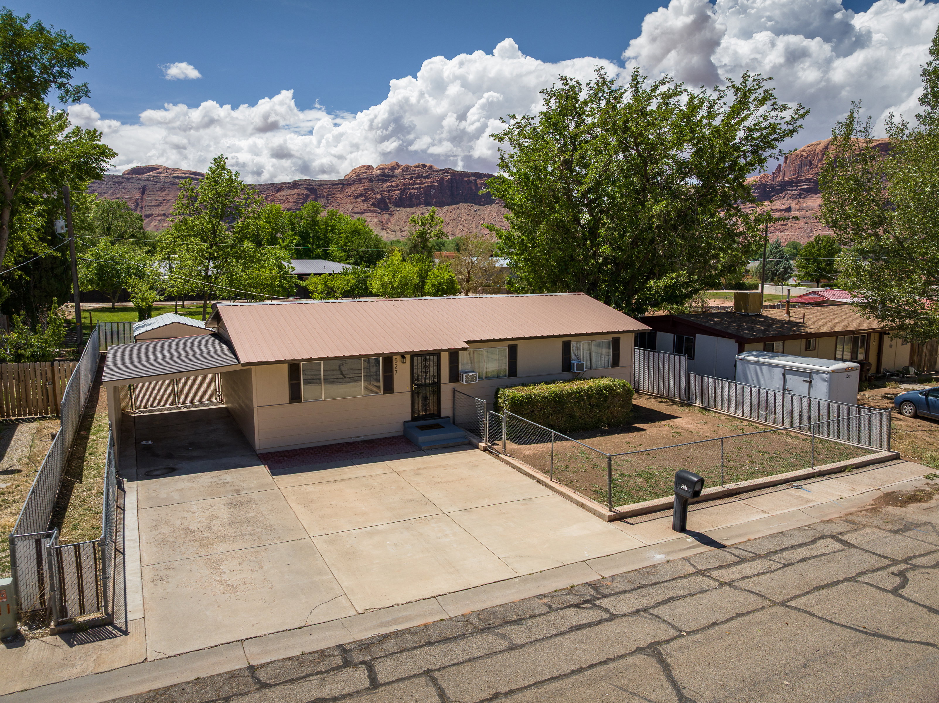 Single story home with a mountain view, driveway, a fenced front yard, metal roof, and an attached carport