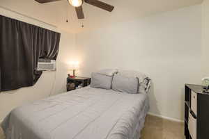 Carpeted bedroom with a ceiling fan, baseboards, and cooling unit